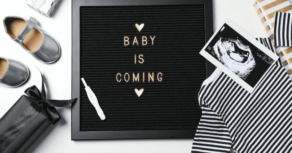 A box of baby items, including baby shoes, a sonogram, and baby clothes, arranged as a creative pregnancy announcement