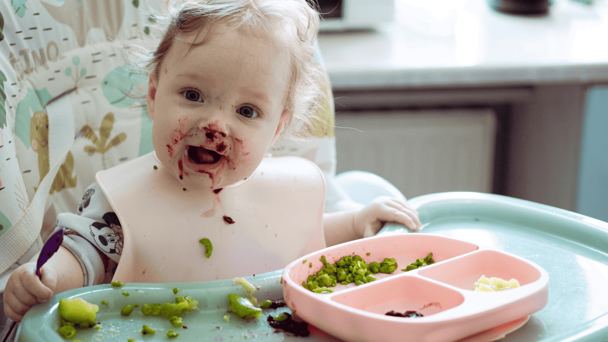 baby girl messy eating with spoon